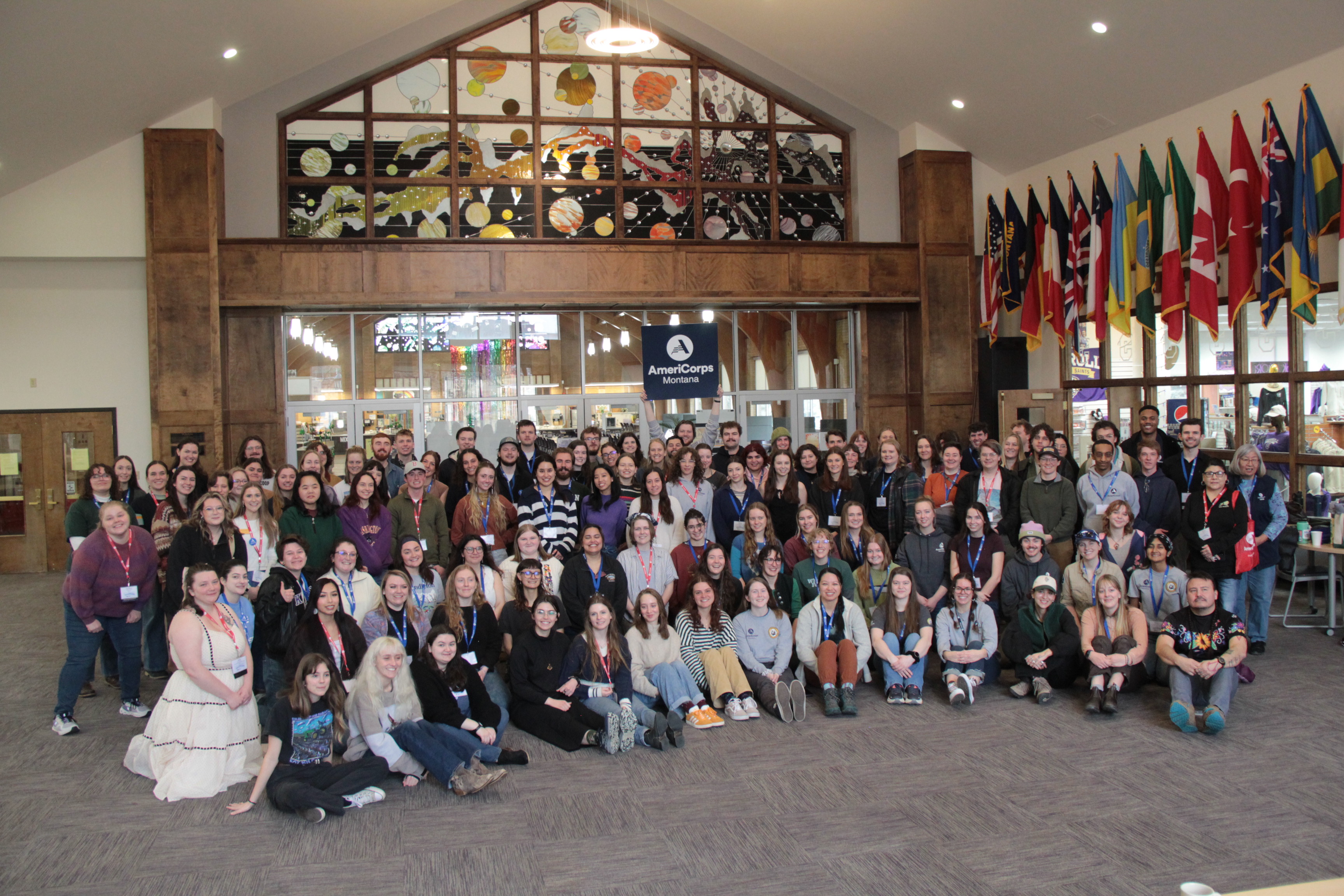 large group of individuals standing on staircase holding AmeriCorps logo